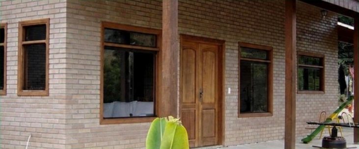 Fachada de tijolo ecológico com esquadrias e portas de madeira